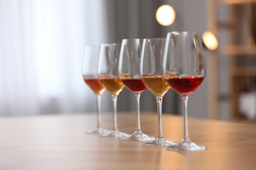 Different sorts of wine in glasses on wooden table indoors. Space for text