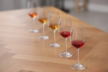 Different sorts of wine in glasses prepared for tasting on wooden table indoors