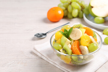 Delicious fresh fruit salad in bowl on table, space for text