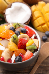 Delicious fresh fruit salad in bowl on wooden table, closeup