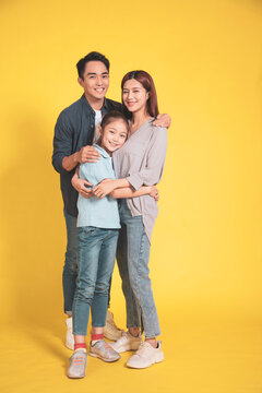 Happy Asian Young Family With One Child Standing Embracing And Smiling