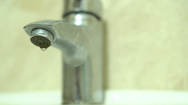 Water dripping from the tap close-up. Scheduled water shutdown and repairs, water saving.