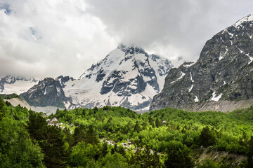 Summer cloudy landscape with Russian Caucasus mountains and forest at the foot of it.
