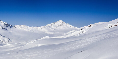 Fototapeta na wymiar Snow covered Ullukambashi mount and Hotu-Tau plateau in sunny winter day, view from Elbrus ski slope in Kabardino-Balkaria, Russia.