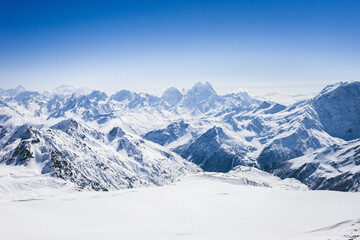 Fototapeta na wymiar Snowy winter Greater Caucasus mountains at sunny day. View from ski slope Elbrus, Kabardino-Balkaria, Russia
