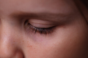 Fototapeta na wymiar close-up macro eye of a Caucasian girl with long dark lashes and a downcast, sad look.