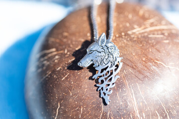 Pendant wolf head necklace silver outside in a summer day closeup. Selective Focus. High quality...
