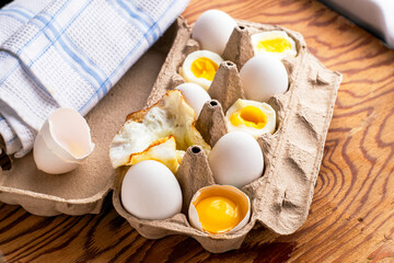 eggs in a cardboard box on the table some eggs are whole others are in different degrees of readiness