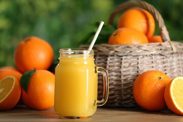 Delicious orange juice and fresh fruits on wooden table against blurred background