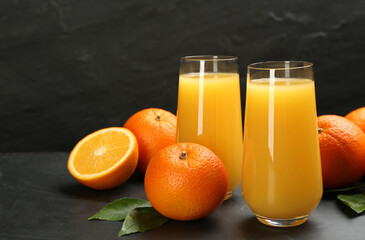 Delicious orange juice and fresh fruits on black table