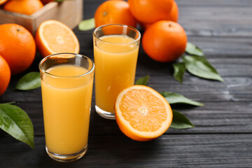 Delicious orange juice and fresh fruits on black wooden table