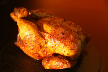 Delicious grilled whole chicken on black table