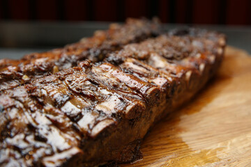 Tasty grilled pork ribs on wooden board, closeup