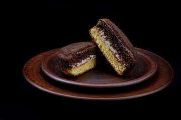 Two halves of tiramisu cake on a clay plate.