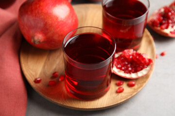 Pomegranate juice and fresh fruits on grey table