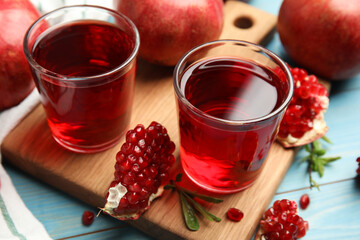 Pomegranate juice and fresh fruits on light blue wooden table