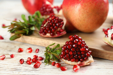 Fototapeta na wymiar Delicious ripe pomegranates on white wooden table, closeup
