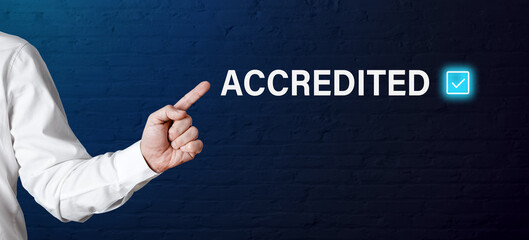 Businessman hand points to the word accredited