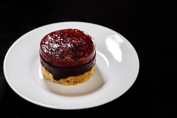 Sponge cake on a plate covered with raspberry jelly on top.