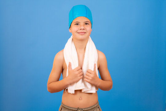 Young boy smiling with swimmer cap and towel over blue background