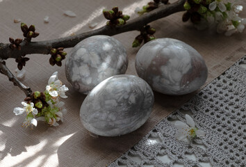 Easter eggs and cherry twigs by the window on a tablecloth.