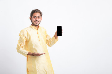 Young indian man in tradition wear and showing smartphone screen on white background.