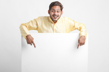 Indian man holding white board, promoting offers on festival season while wearing traditional cloths, standing over white background.