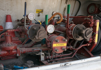 LPG tank refueling performed by a skilled worker with appropriate pipes connected to the truck with pressure gauges and pipes in evidence