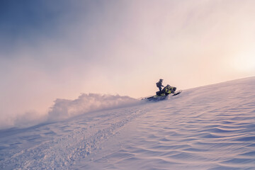 Silhouette of Rider on snowmobile during sunset in beautiful landscape