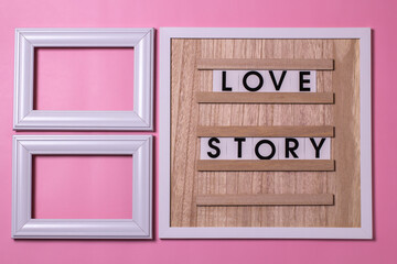 love story with photo frame, on the board lying on a pink background.