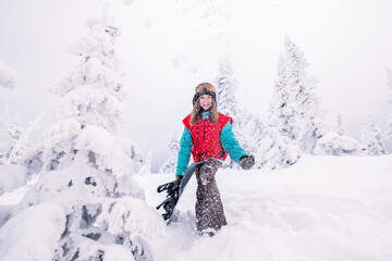 Fototapeta na wymiar Happy snowboarder woman holding snowboard during Powder Day, winter holiday in ski resort