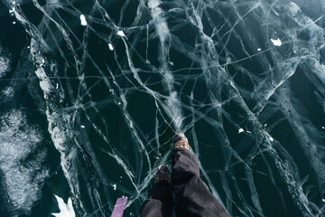 Traveler's feet standing on the frozen ice of Lake Baikal