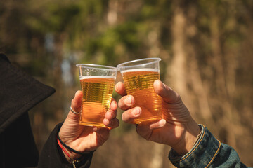Hands of women say goodbye to beer and plastic cups in the park in the sunlight
