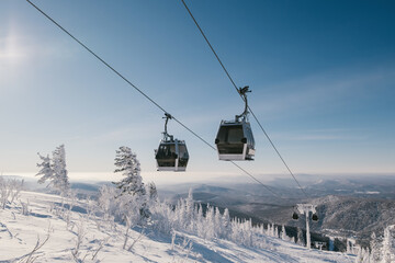gondola ski lift in mountain ski resort, winter day, snowy spruce forest © Annatamila
