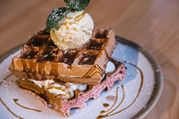 Waffles with caramel, pistachio cream and ice cream on a plate in  restaurant