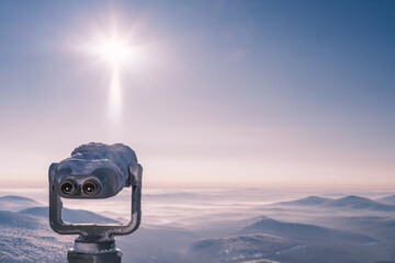Frozen, snow covered touristic Coin Operated Binocular viewer over mountain skyline winter landscape.