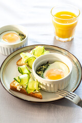 Shirred eggs (Oeuf cocotte) or baked eggs. healthy breakfast with eggs and spinach and toast with cucumber