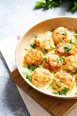 meatballs in white sauce in a frying pan on a gray background, comfortable homemade healthy food
