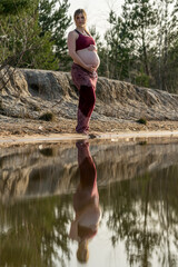 Pregnant woman standing at a lake 