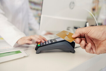 Payment by card at the pharmacy. Male hands provide a payment credit or debit card to the terminal...