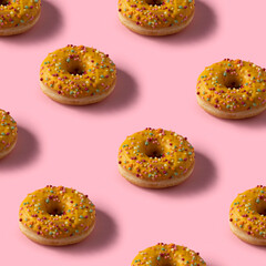 Donuts pattern image.Yellow glassed donuts on pink square background.