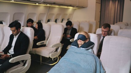 Fototapeta premium Flight Attendant woman covering a blanket for elderly female passengers to sleep well on the plane. Air hostess woman covering tired sleepy elderly with blanket during trip on the airplane.