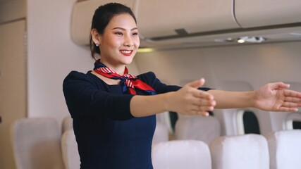 Flight attendants on demonstration aircraft in emergencies, Female flight attendant points out emergency exits during safety briefing in commercial airline main cabin.