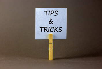 Tips and tricks symbol. White paper on wooden clothespin. Words 'Tips and tricks'. Beautiful grey...