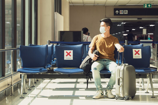 New Normal travel during covid-19 pandemic concept. An asian man with face mask keep social distancing at the airport terminal ready to boarding. Stop asian hate, Quarantine, Entry restrictions.