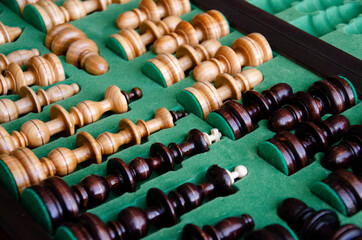 Wooden chess pieces in the playing box with green background