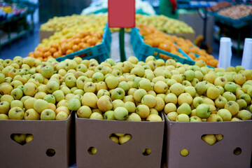 Boxes of apples against fruits on the shelves in the supermarket.