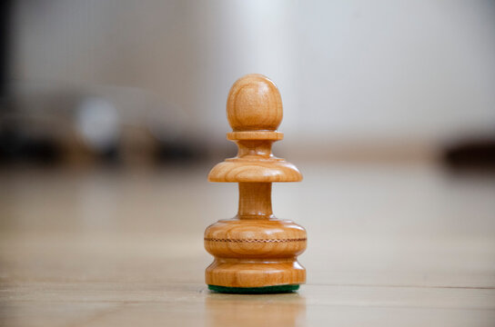 Chess board game, white wooden pawn in focus. Chess pieces with blurred background.