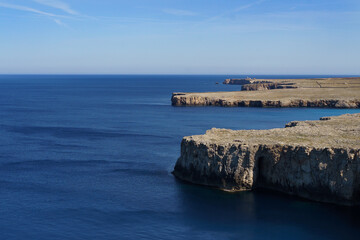 View of Punta Nati lighthouse from Sa Falconera point of view (Menorca, Balearic Islands, Spain) in a sunny day with blue sky