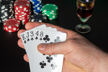 Poker cards flush combination. Close up of a gambler hand is holding playing cards and sigar in poker club